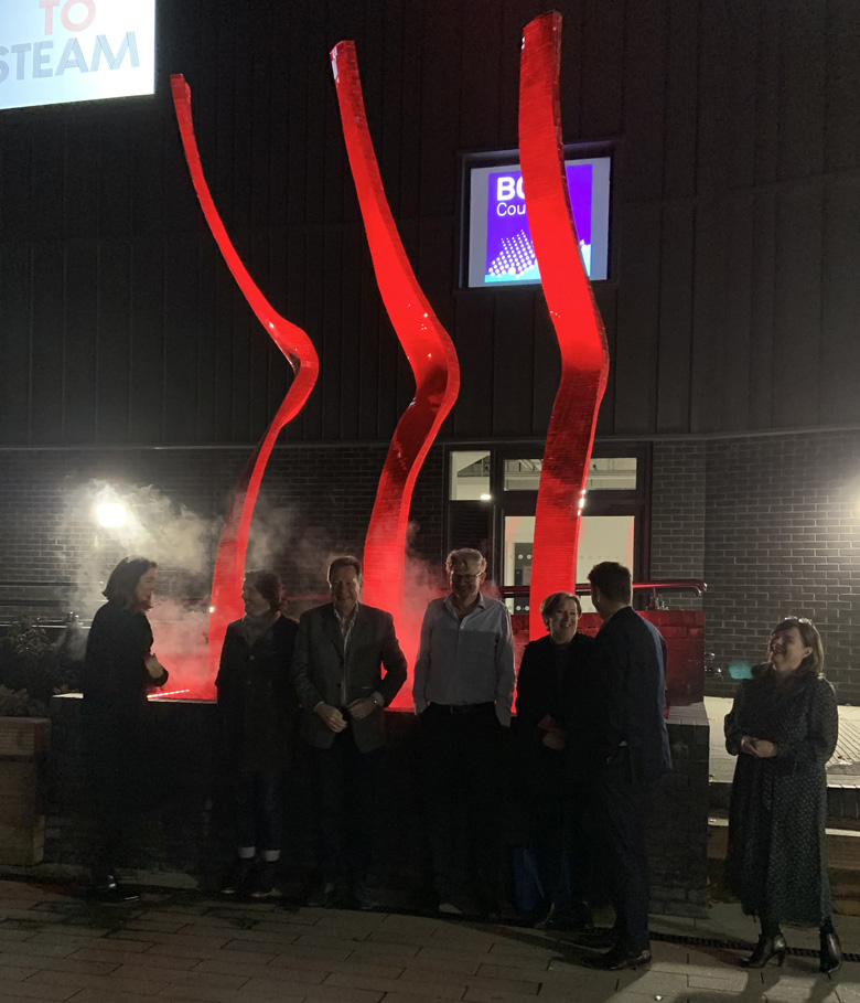 This photo shows a collection of three, red, mosaiced sculptures called Surge by Rebecca Newnham, and was designed to highlight the importance of Art in STEM. It is made up of three curved sculptures and stands outside the new STEAM building at Talbot Heath School Photographed by David Bird.