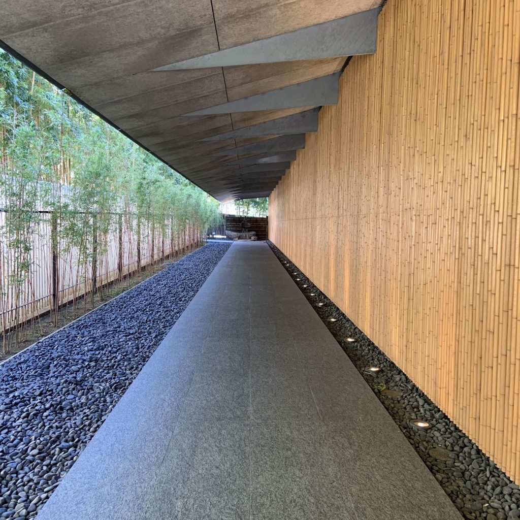 A corridor in the Nezu Museum in Japan is lined with cut bamboo on one side and grey pebbles on the other. Photographed by Rebecca Newnham.