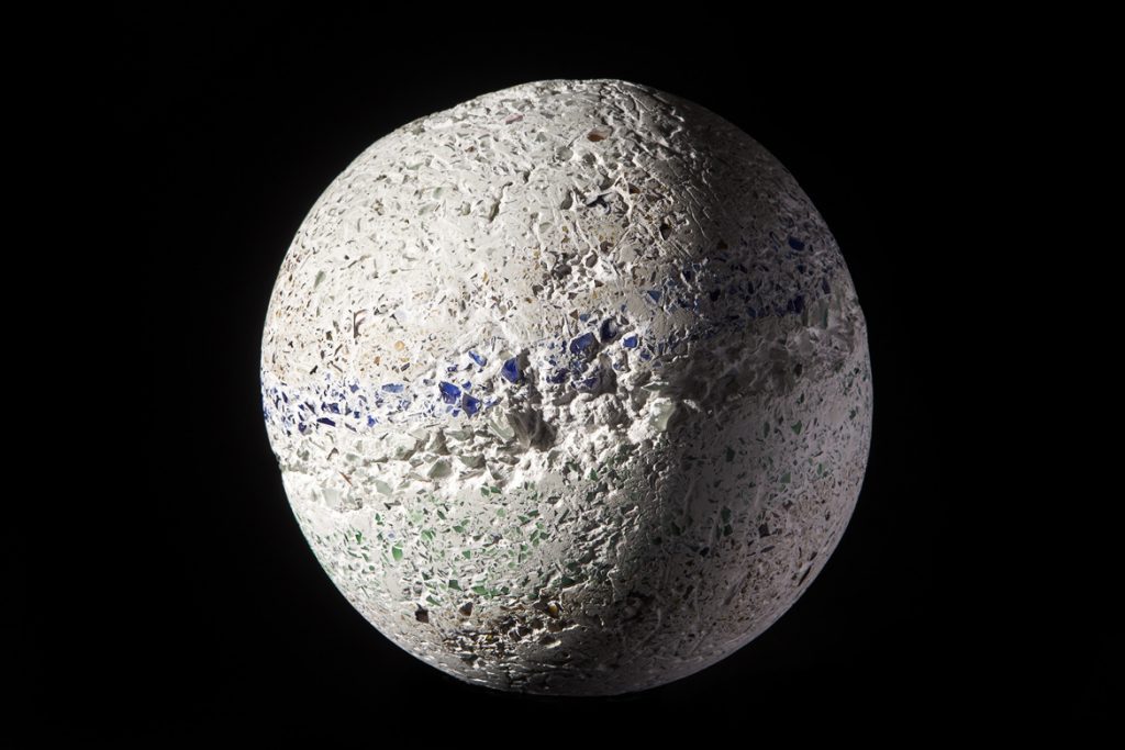 A sphere made of imploded blue glass and concrete by Rebecca Newnham, photographed against a black background. Photographed by David Bird.